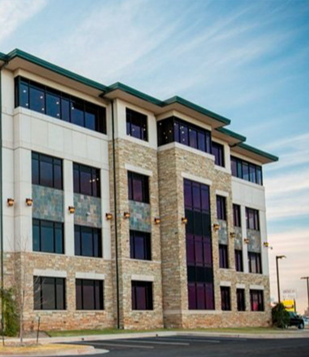 Mid-rise commercial building with a mix of stone and concrete exterior, dark-tinted windows, and a clean, modern architectural style.